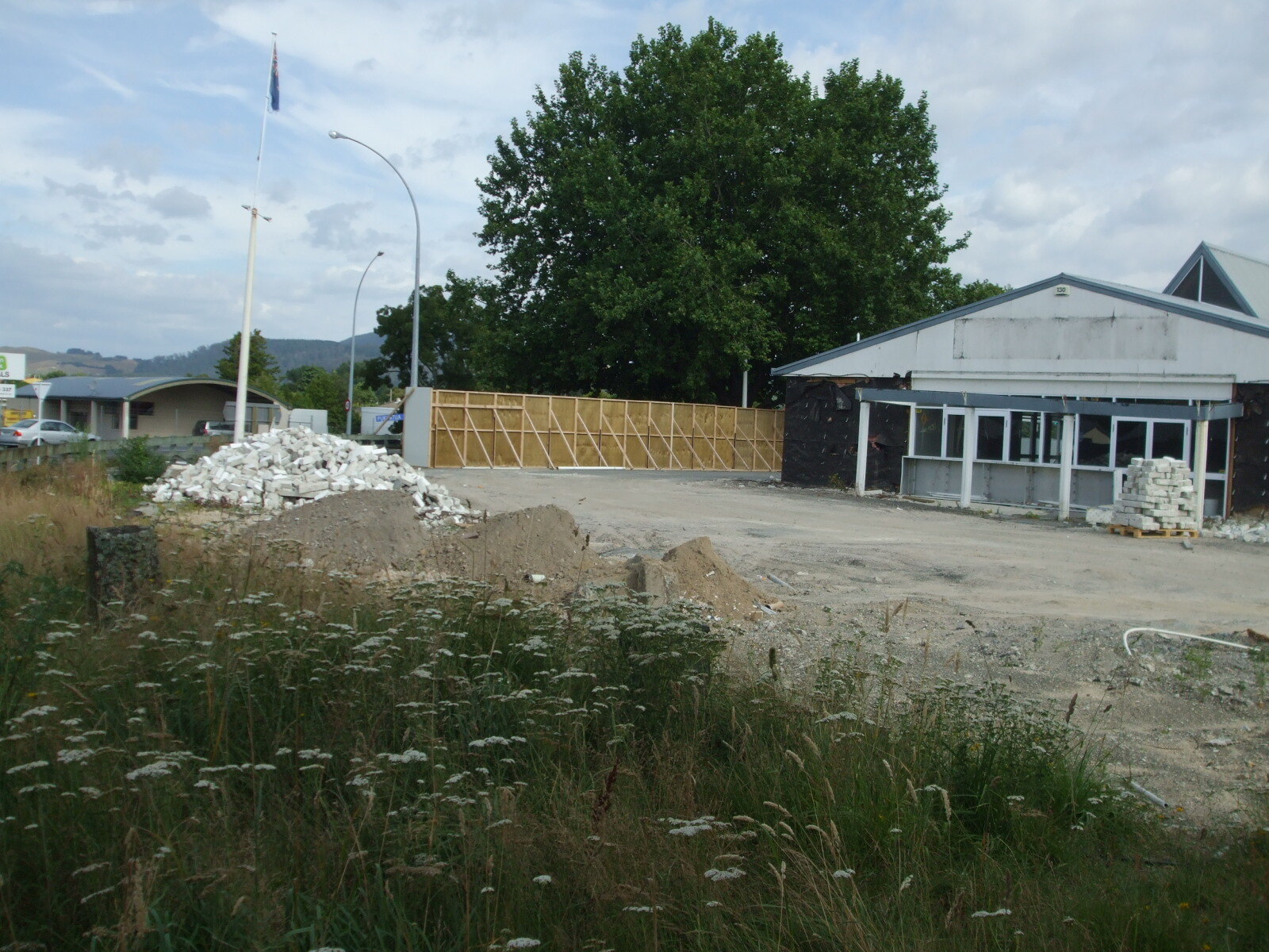 Photograph showing the chapel end of Grey's Funeral Home, with piles of rubble and dirt