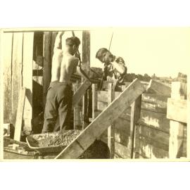 Photograph of Richard Robinson and helper building the new cowshed, ca.1958