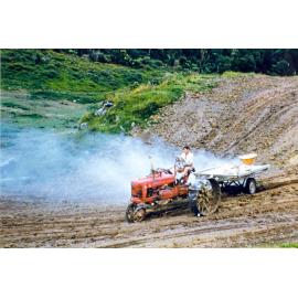 Photograph of Mr Robinson sowing grass for the airstrip, ca.1959