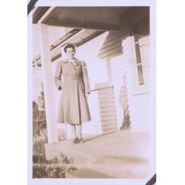 Black and white photograph of an unidentified woman standing on a porch