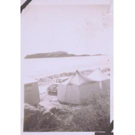 Black and white photograph of a tent pitched on the beach 