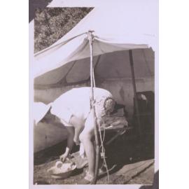 Black and white photograph of a woman rinsing dishes