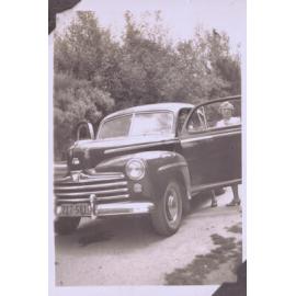 Black and white photograph of a car and two unidentified people