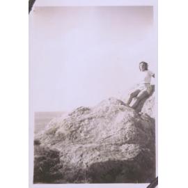 Black and white photograph of a woman leaning against rocks