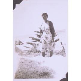 Black and white photograph of unidentified woman in a dress with a coastal seascape behind
