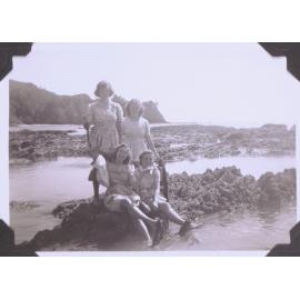 Black and white photograph of six-form students on a weekend at Ōhope titled "Four damsels on the rocks of Shelly Bay"