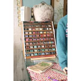 Photograph of some haberdashery, showing a rack of cotton spools
