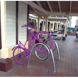 Photograph of old painted bicycle, parked in front of the iSite building